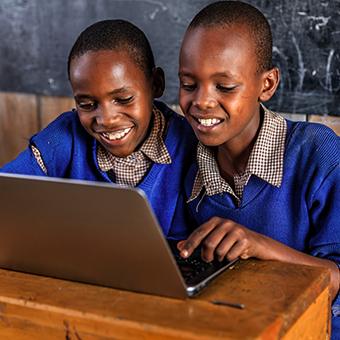 非洲的两个男生对着一台笔记本电脑微笑
